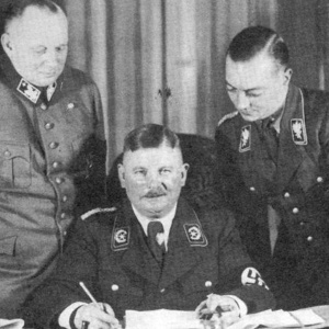 Ernst Röhm (Mitte) kurz nach seiner Ernennung zum Minister ohne Geschäftsbereich im Kabinett Hitler (Dezember 1933). Rechts SA-Gruppenführer Karl Ernst, links Franz von Stephani (in der Tunika des Stahlhelms). | Federal Archive Lichterfelde (Public property in accordance with the Berlin Document Centre Regulations).